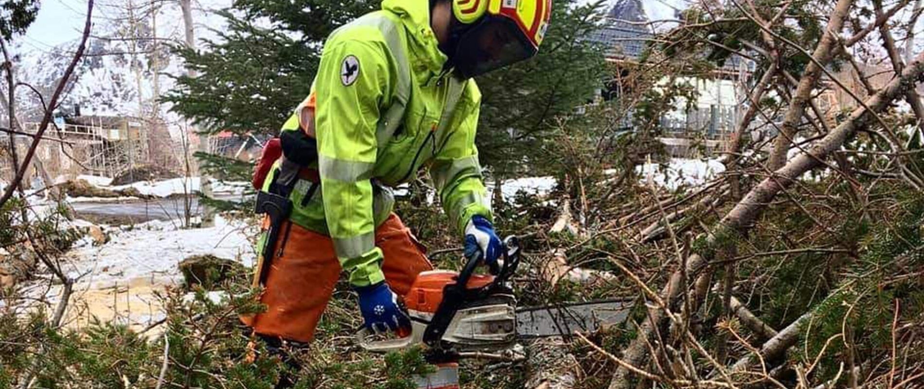 hombre cortando una rama con motosierra en un pueblo que se encuentra en una montaña nevada